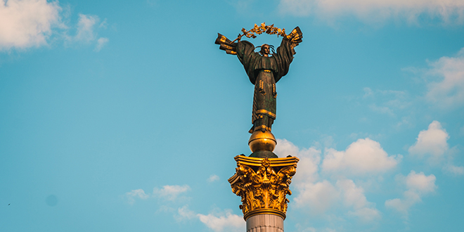 Monument med en statue av en kvinne som holder en gren med korsved i armene.