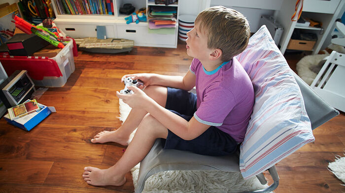 A pgotography of a young boy sitting in a kid room, playing video games.