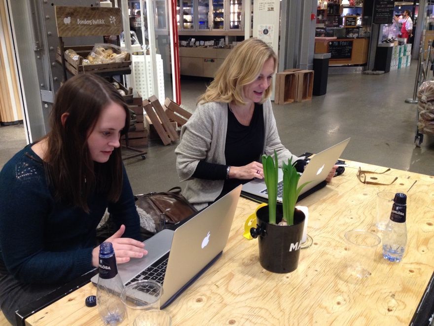 Two females look at two lap tops.