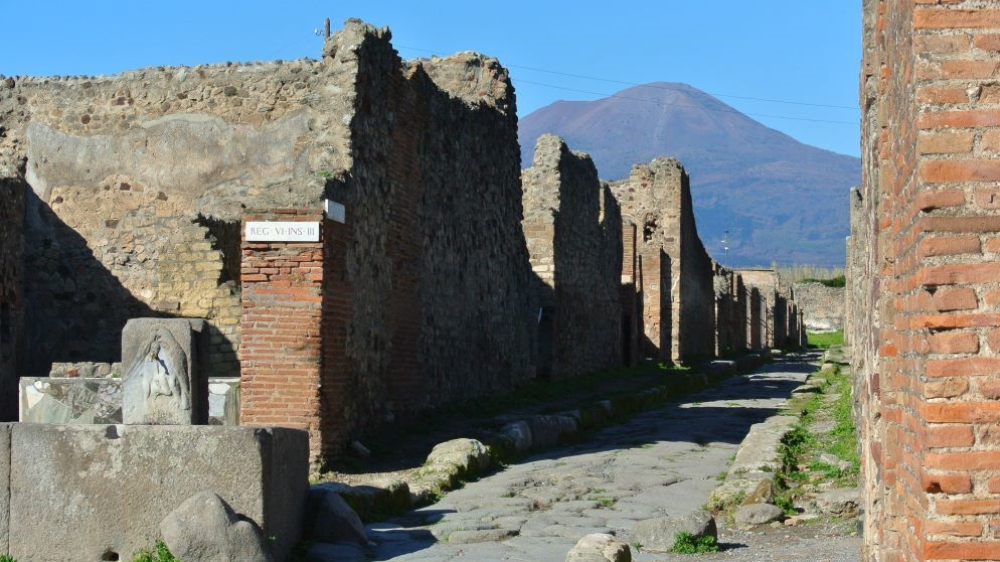 Pompeii, utgravningsområde med bygninger, vei og vulkanen Vesuv i bakgrunnen