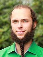 En ung mann med grønn skjorte, mørkt hår og skjegg.
