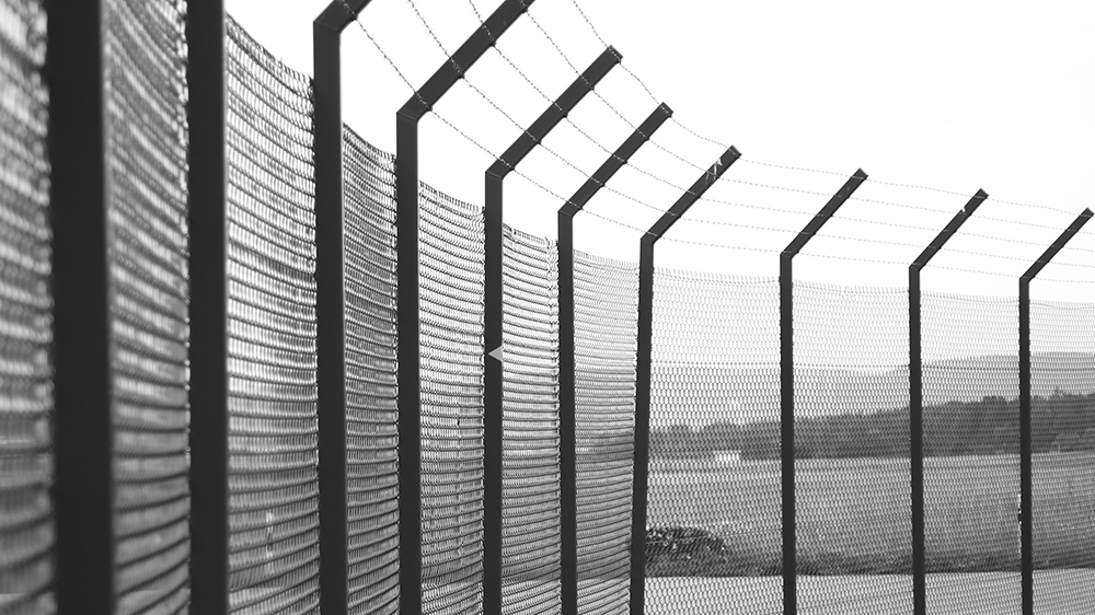 A high fence with a landscape in the background. Photo.