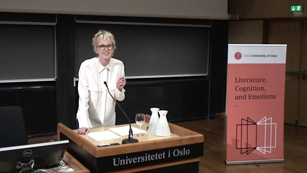 A middle aged woman, Siri Hustvedt, in a white shirt holding a lecture. Photo.  