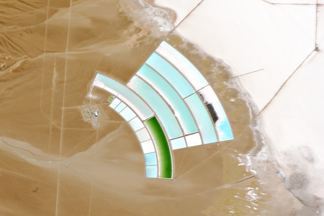 This image shows several basins shaped like arches. The basins are part of a lithium mine located in Argentina, and their blue contents contrast with the dessert around.
