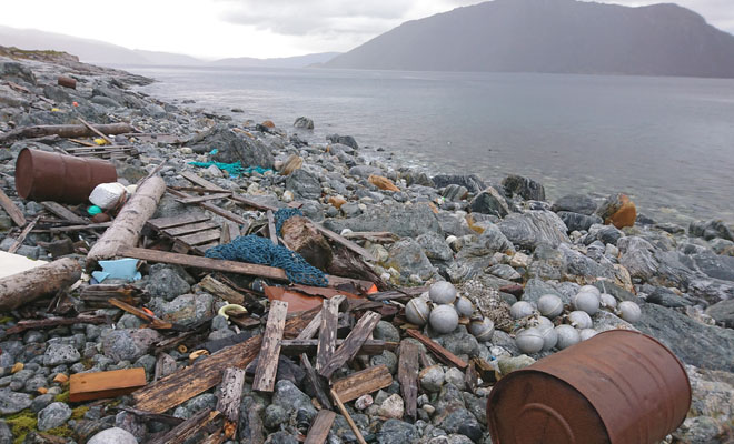 Photo of trash and scrap on a rocky beach. 