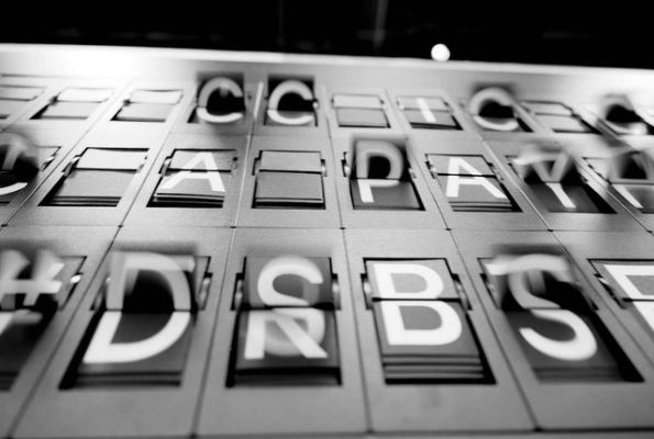 Black and white image of a split-flap display with letters and numbers.