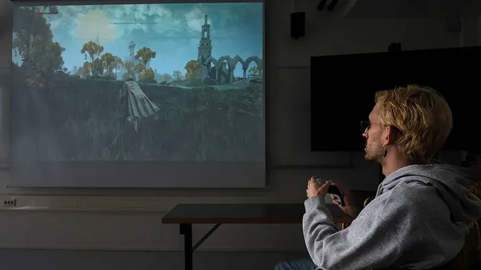 Image contains a young man who is playing a video game
