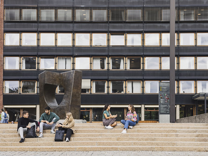 Students sitting and talking on a staircase in front of a university building (P. A. Munch's house). Photo.