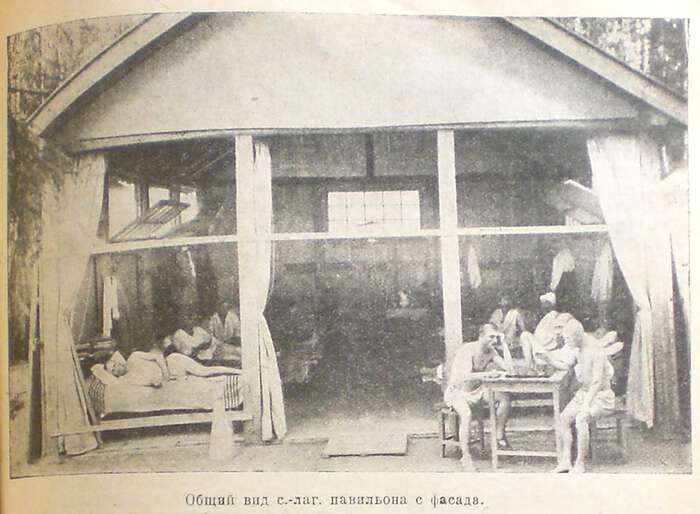 Historic black-and-white photograph of a sanatorium-camp pavilion with open curtained bays and people resting inside.