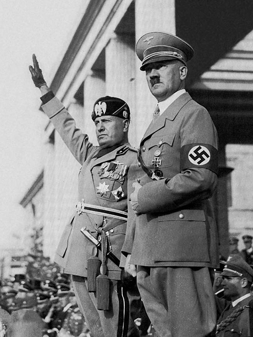 Svart hvitt bilde av Mussolini og Hitler. To uniformskledde menn, den ene holder hånden hevet. 