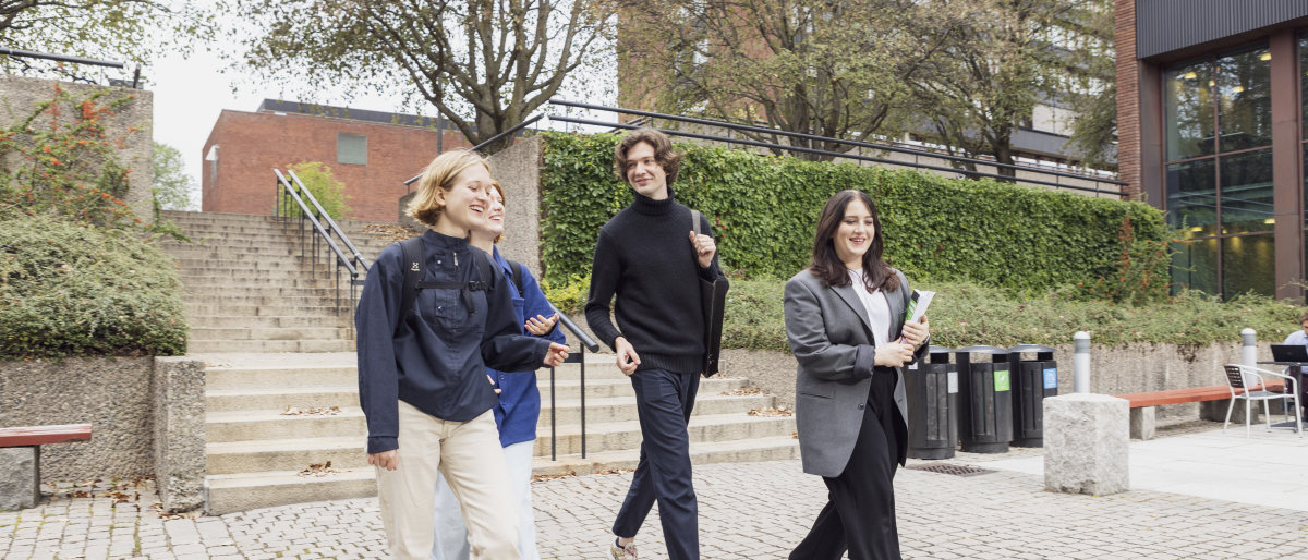 Fire studenter som går foran Georg Morgenstiernes hus, IFIKK. Foto.