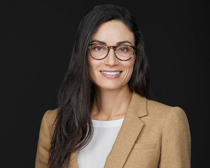 Portrait og smiling woman with dark hair and glasses.