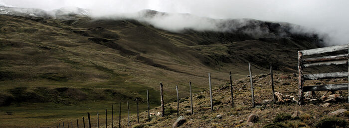 Landscape with hills, clouds and a wooden fence. Photo.