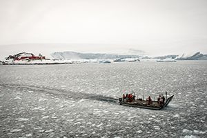 Small boat with people on in the sea with ice. Photo.