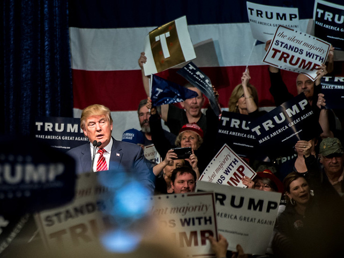 Donald Trump surrounded by posters with his name on.