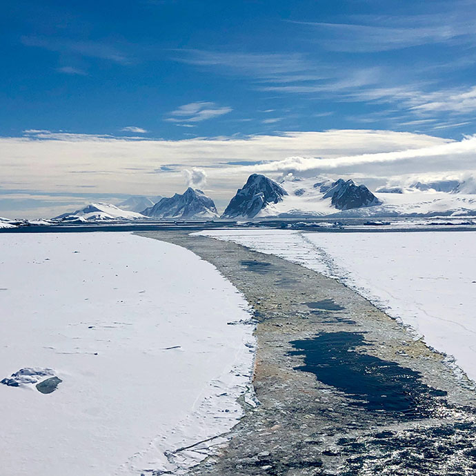 Is og fjell på Antarktis mot blå himmel