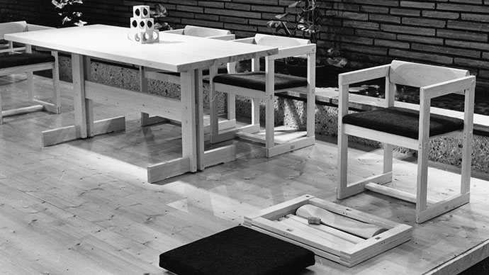 A black and white photo of a dining table and dining chair made of pine.