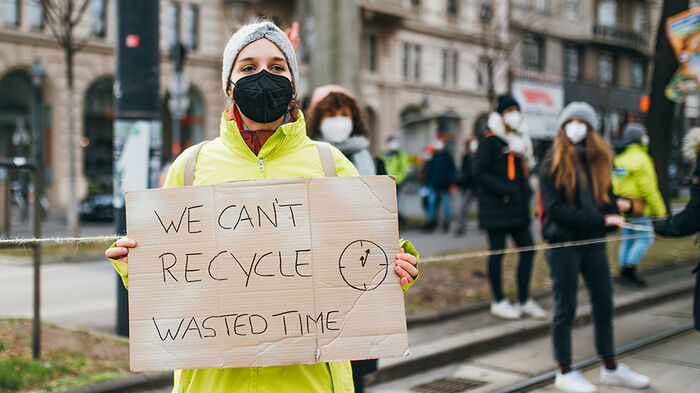 En kvinne demonstrerer i en by om klimapolitkk. Med plakat.