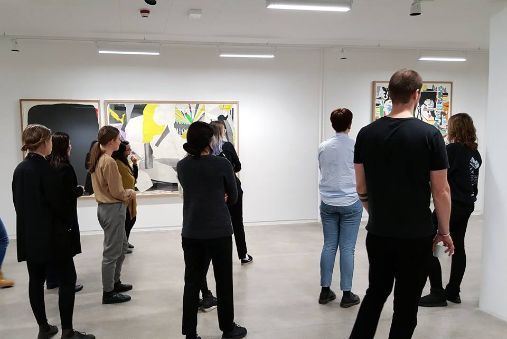 Mennesker som ser på kunst i et hvitt galleri.