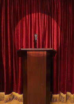 empty lectern in front of red curtain