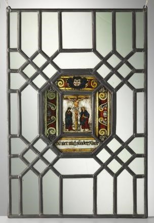 Glassmaleri bestående av grafiske metalllinjer og hvitt glass som omslutter et mindre bilde med et religiøst motiv. Foto.