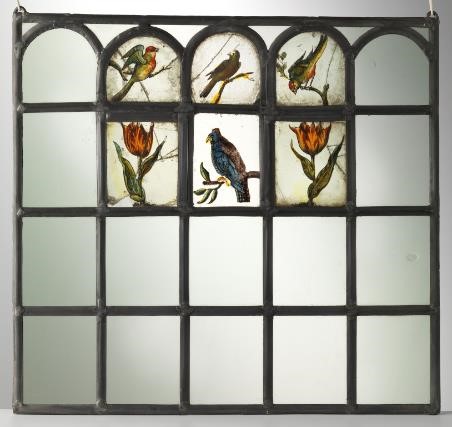 Glassmaleri med fem ganger fire ruter av metallstenger og hvitt glass. Seks av de øverste rutene er dekorerte med blomster og fugler. Foto.