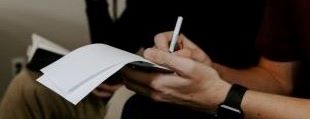 Man making notes which illustrates content labeled "in the media"