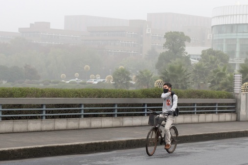 Photo: In addition to water pollution, air pollution is also among the biggest environmental issues in China today. This photo shows a university student riding his bike through campus at Zhejiang University wearing a face mask for protection against the smog. (Author’s photo)