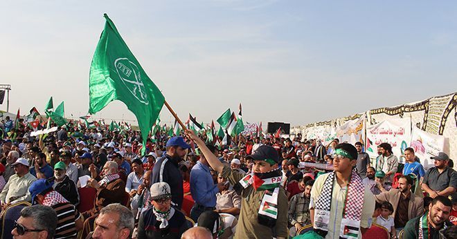 Mange menn demonstrerer, en ung gutt holder et grønt flagg. 