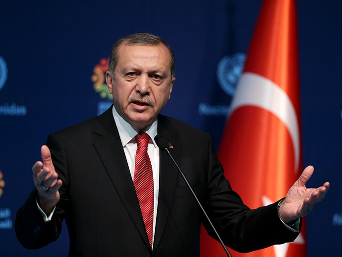 President Erdogan speaking. Elderly man wearing suit and tie. The turkish flag in the background.