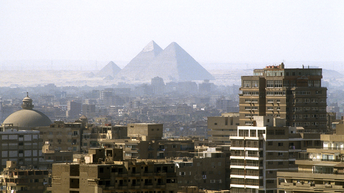 Oversikt over byen med bygninger og pyramider i bakgrunnen. Foto.