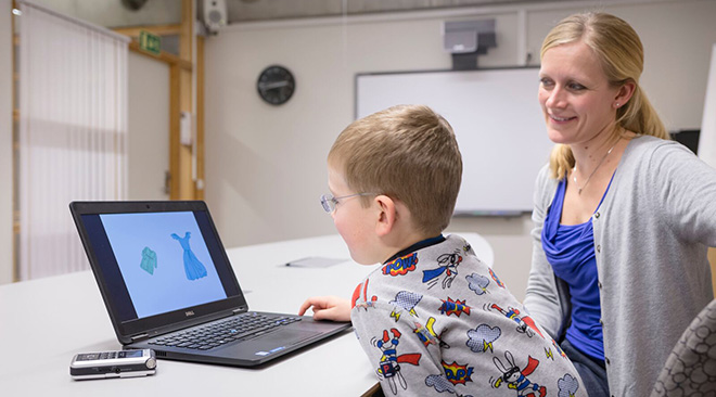 Barn ser på dataskjerm, mens kvinnelig forsker ser på.