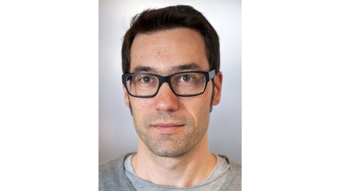 Portrait of Stijn Vervaet. A man in his 40s with glasses and dark hair. 
