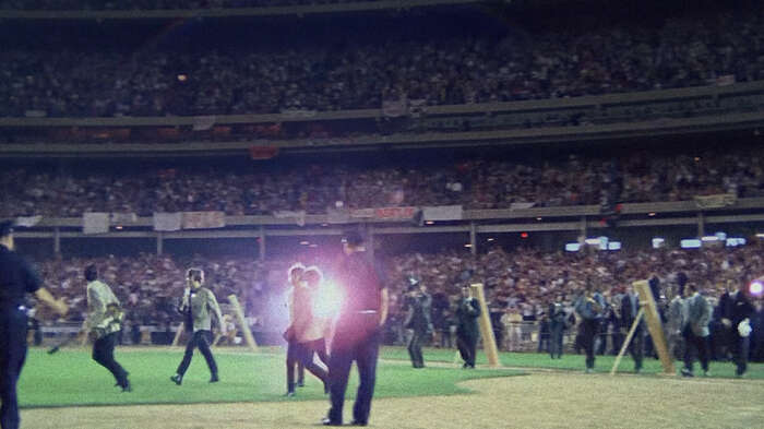 The Beatles walk across the baseball field at Shea Stadium for their historic concert.