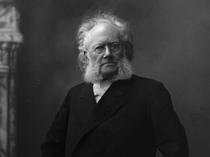 Black and white portrait of Henrik Ibsen. Old man with white hair and glasses, black suit.
