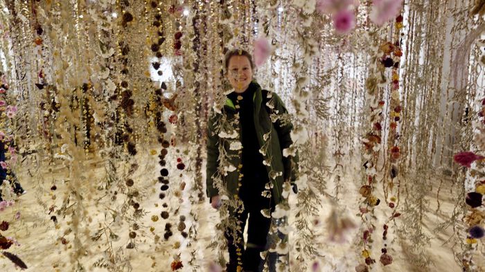 photo of Larissa Lily walking through a flower installation