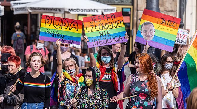Demonstranter med masker og plakater i regnbuefarger.