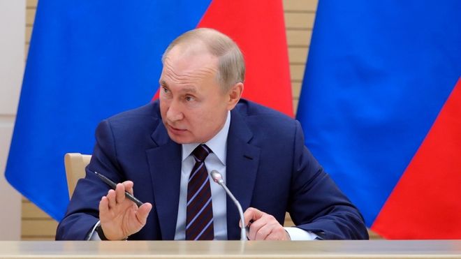 President Vladimir Putin snakker, har russiske flagg bak ham.