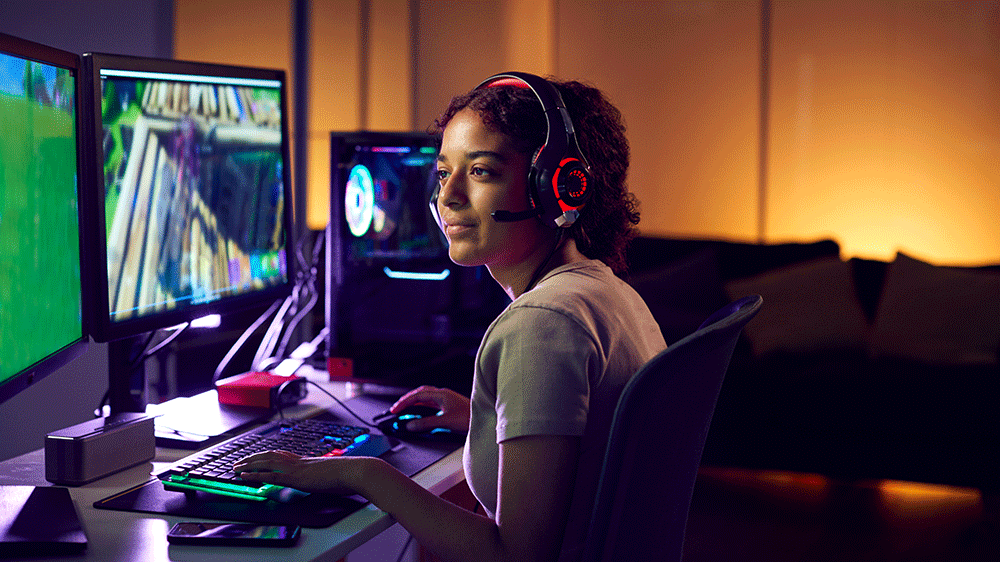 A young girl with headphones in front of several pc screens.