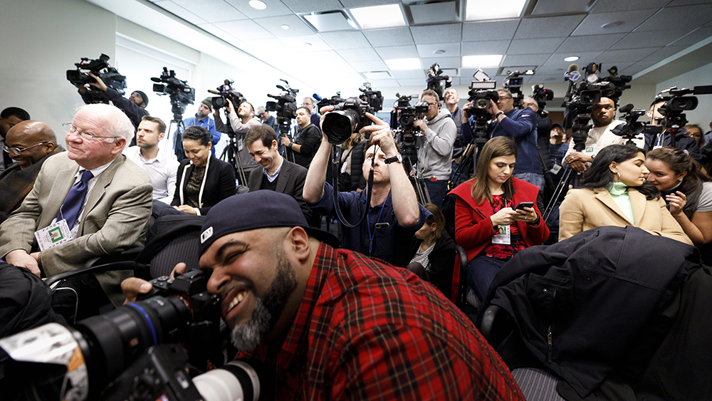 Et rom fylt med pressefolk med kameraer og mobiltelefoner.
