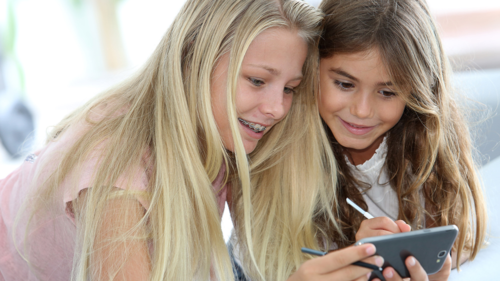 Two girls looking at a smartphone together, smiling