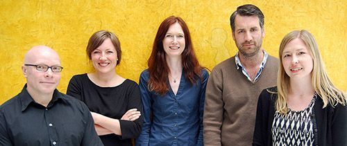 Five people in front of a yellow wall.
