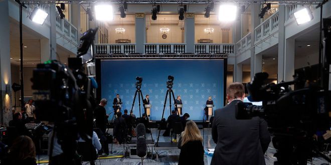 Regjeringen holder pressekonferanse. Journalister og kameraer vises i forkant. Foto.