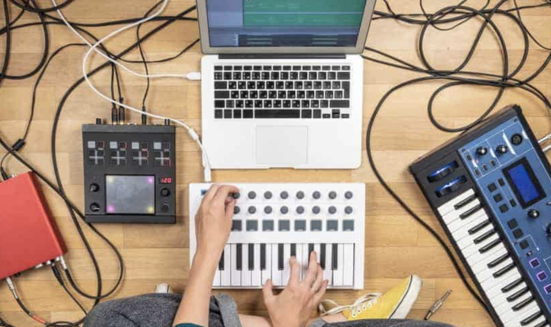 En person spiller musikk med et keyboard og en laptop.