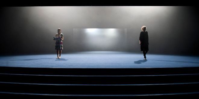 To kvinner med avstand til hverandre på en mørklagt scene.
