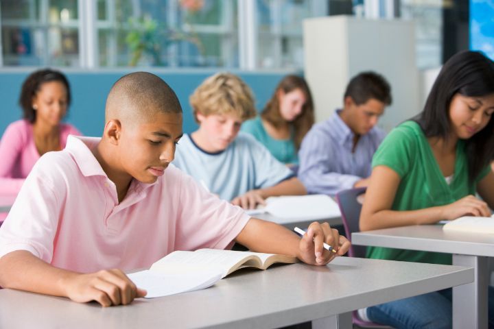 Bilde fra et klasserom, utsnitt med seks elever som sitter ved pultene sine og leser.