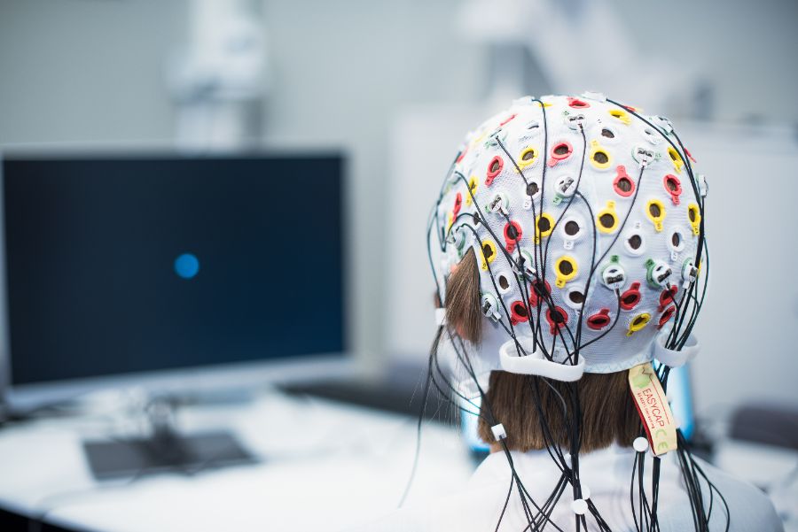 Bildet av ei jente i laben med EEG-hetta på