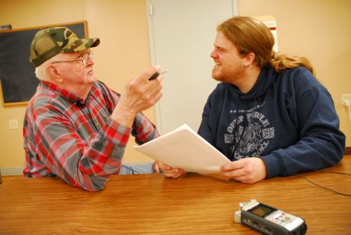 En eldre og en yngre mann snakker sammen. Foto.