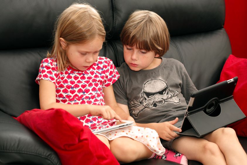 To barn som ser på hver sin skjerm.