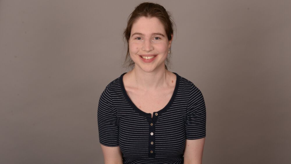 Smilende kvinne med brunt hår og stripete t-skjorte. Foto. 